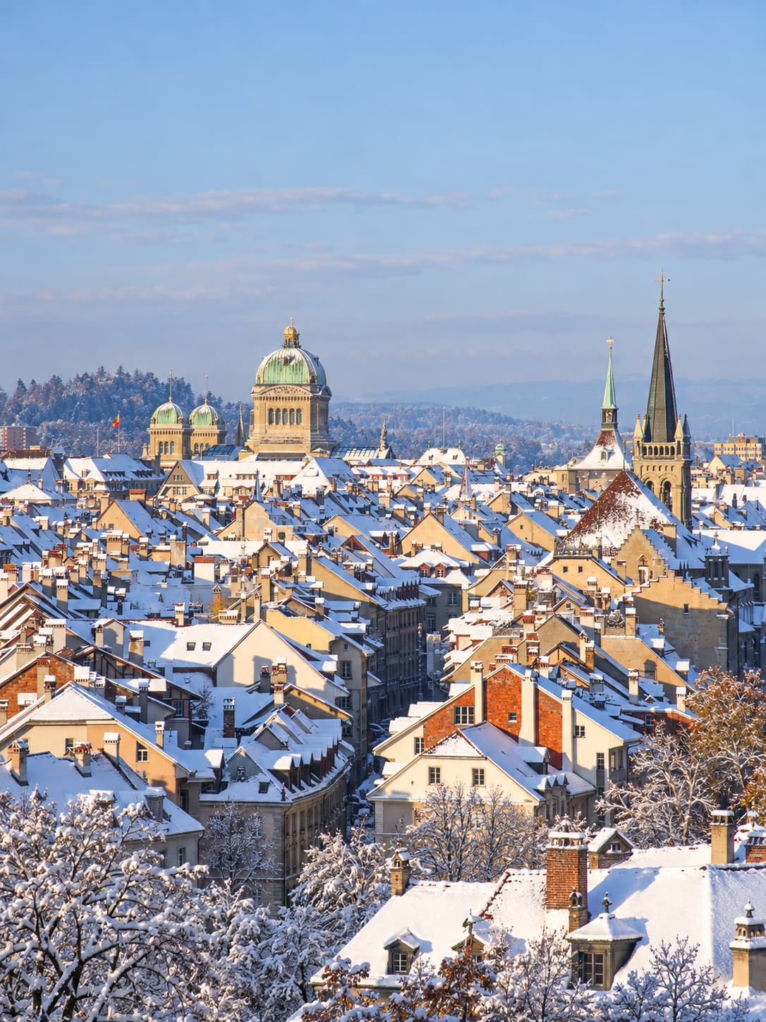 Aerial view of Bern old town blanketed in snow — a base city for switzerland in winter without skiing, Federal Palace dome and church spires rising above the rooftops