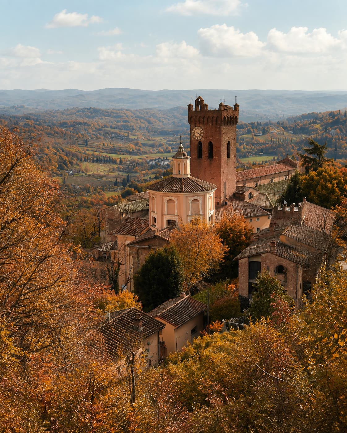Hilltop Tuscan town with a brick clock tower rising above autumn foliage — Tuscany in autumn near San Miniato's truffle country