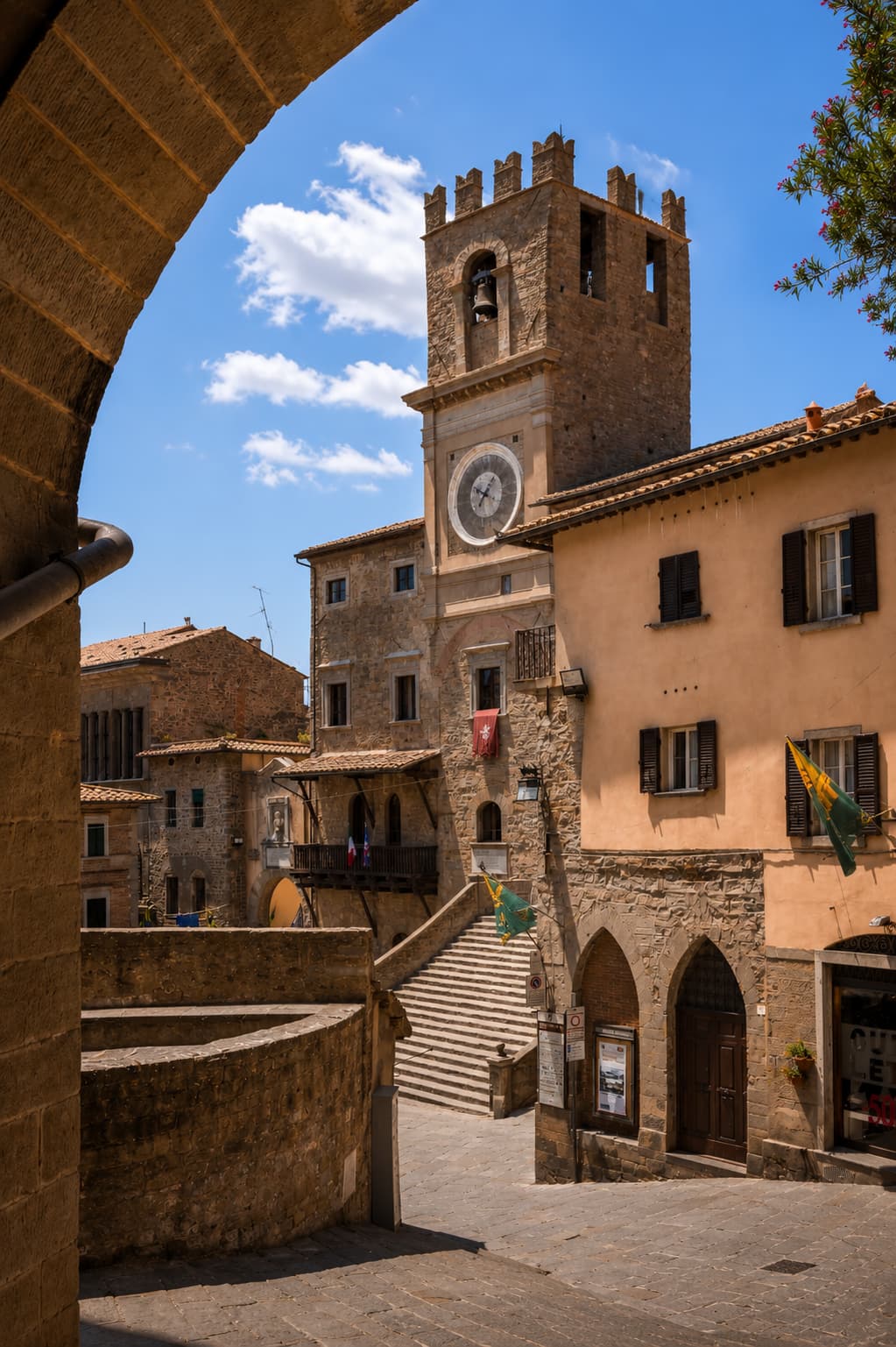 A stone clock tower and staircase in Cortona's quiet old-town square